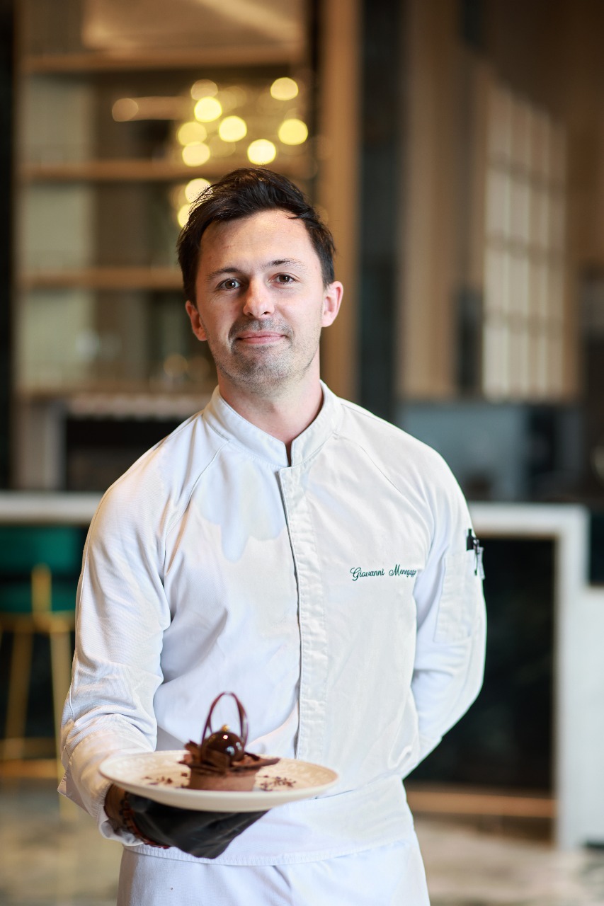 Giovanni Menegazzi in chef whites presenting a plated chocolate dessert